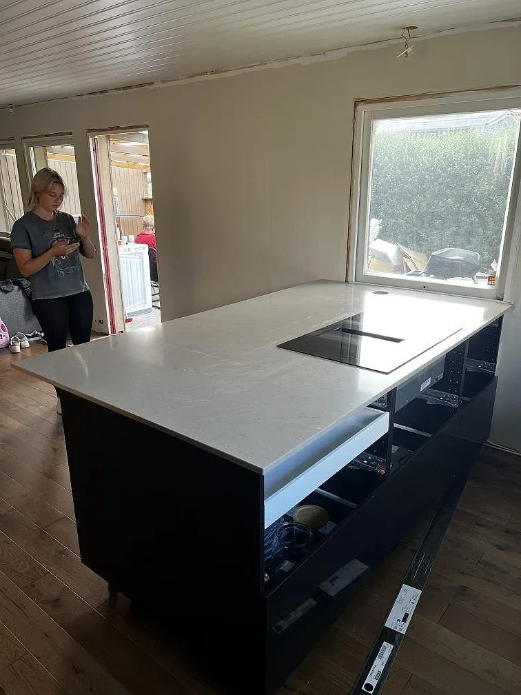 Polerad Silestone Coral Clay på köksö med svart induktionshäll, mörka stommar och fönsterljus i Kalmar.