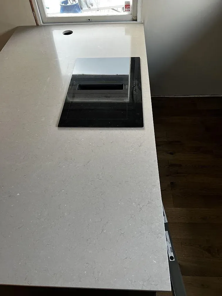 Detalj av polerad Silestone Coral Clay med svart häll och varm gråbeige yta i ett kök i Kalmar.