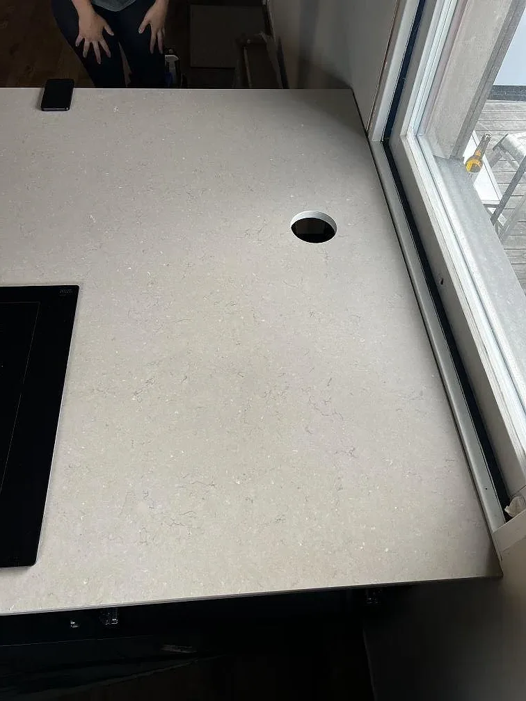 Köksö i polerad Silestone Coral Clay med blandarhål, svart häll och fönsterljus under montering i Kalmar.