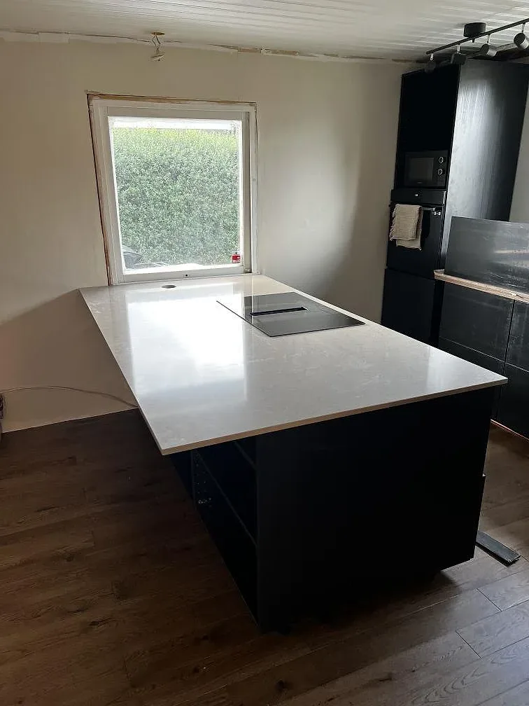 Köksö med bänkskiva i polerad Silestone Coral Clay, varm gråbeige komposit, i ett kök under montering i Kalmar.