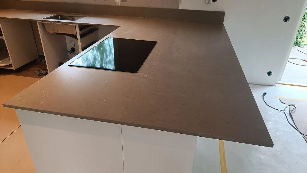 Närbild av köksbänkskiva i Silestone Coral Clay med häll i halvön och vita stommar i Kalmar.
