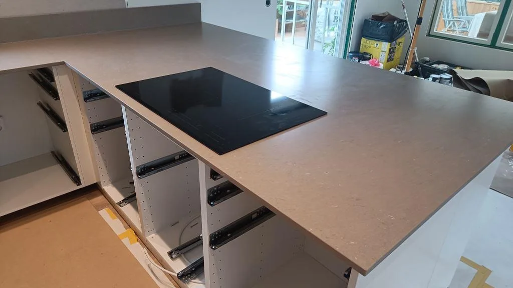 Halvö i Silestone Coral Clay komposit med matt Mocka-yta och svart häll under montering i Kalmar.