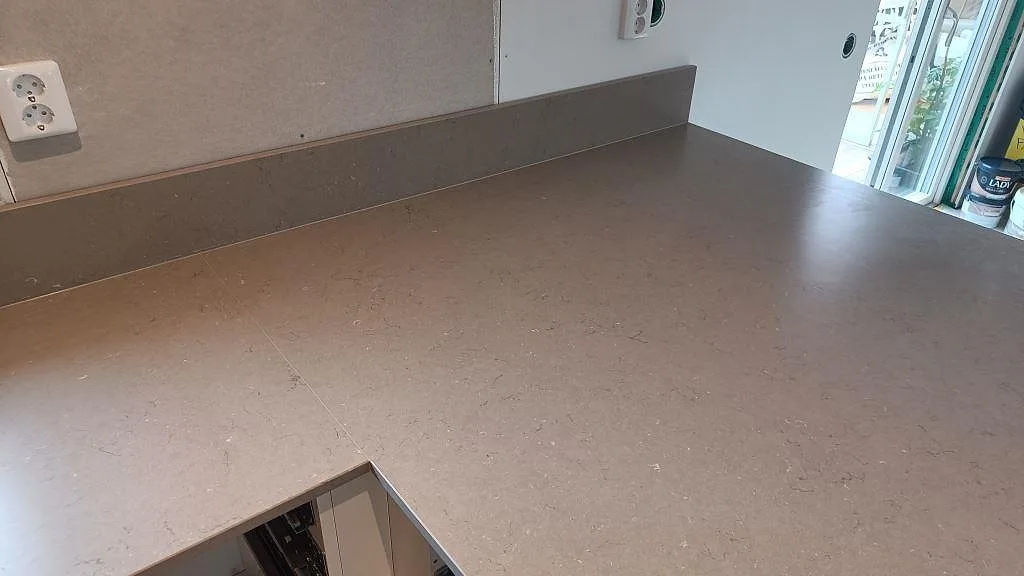 Bänkskiva och låg stänkkant i Silestone Coral Clay, matt komposityta längs väggen i Kalmar.