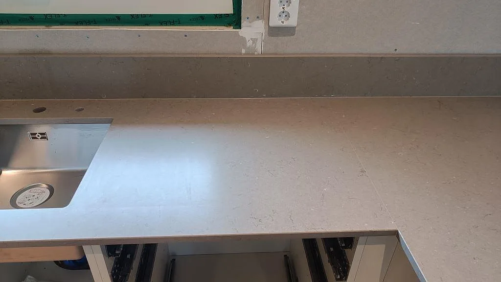 Köksbänkskiva i Silestone Coral Clay med rostfri diskho, stänkkant och fönster vid montering i Kalmar.