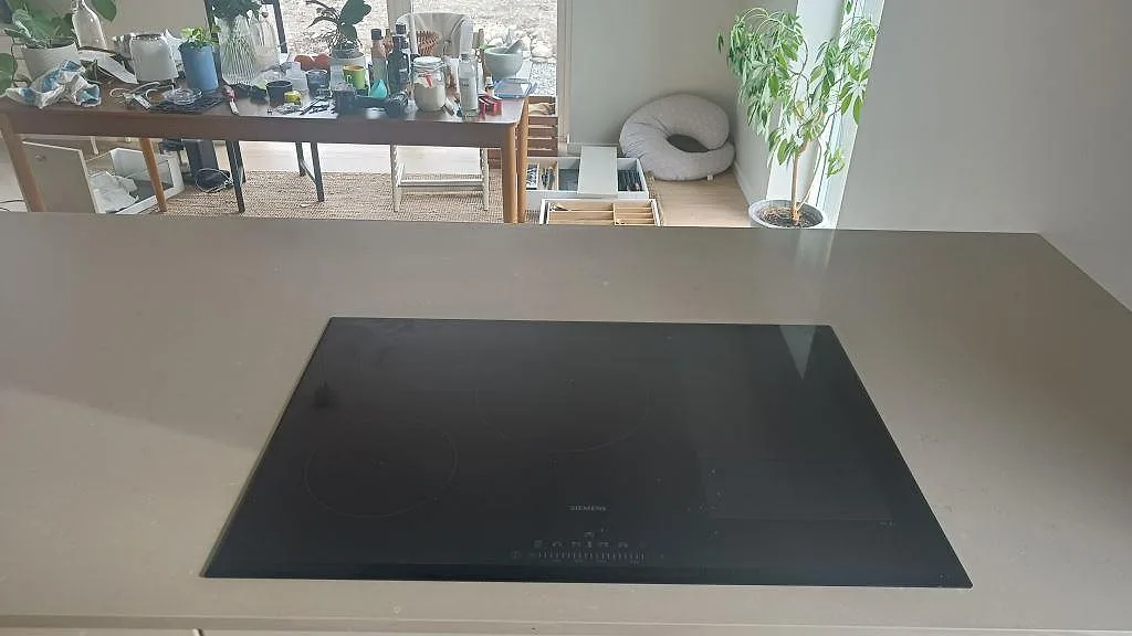 Induktionshäll från Siemens infälld i en polerad köksbänkskiva i Silestone Coral Clay i ett kök i Kareby.