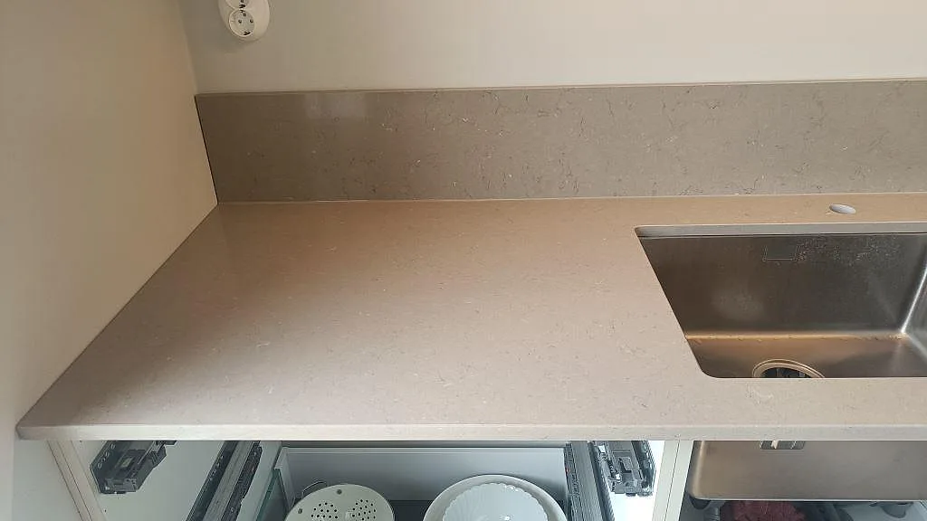 Polerad bänkskiva i Silestone Coral Clay med uppvikt stänkkant och underlimmad rostfri diskho i ett kök i Kareby.