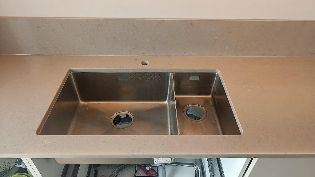 Två underlimmade rostfria diskhoar i en polerad köksbänkskiva i Silestone Coral Clay i ett kök i Kareby.