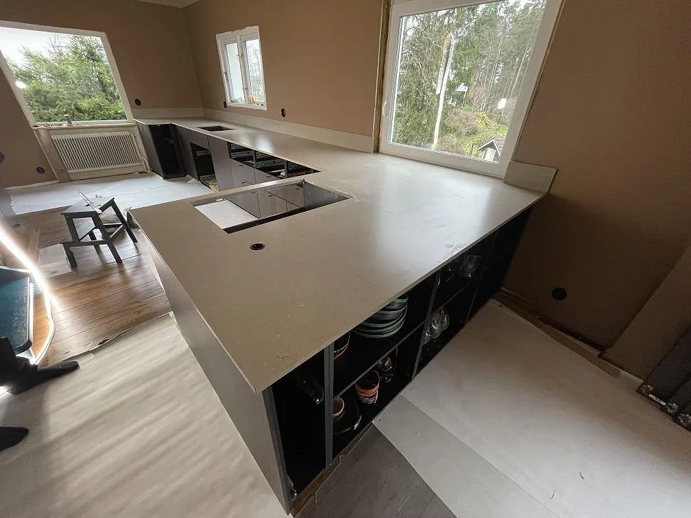 Närbild på den matta kompositytan Silestone Coral Clay på en köksbänk vid stort fönster i Karlskoga.