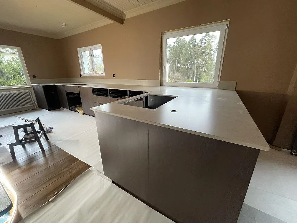 Halvö och lång köksbänkskiva i matt Silestone Coral Clay med stänkskydd i 12 mm under fönstren i Karlskoga.