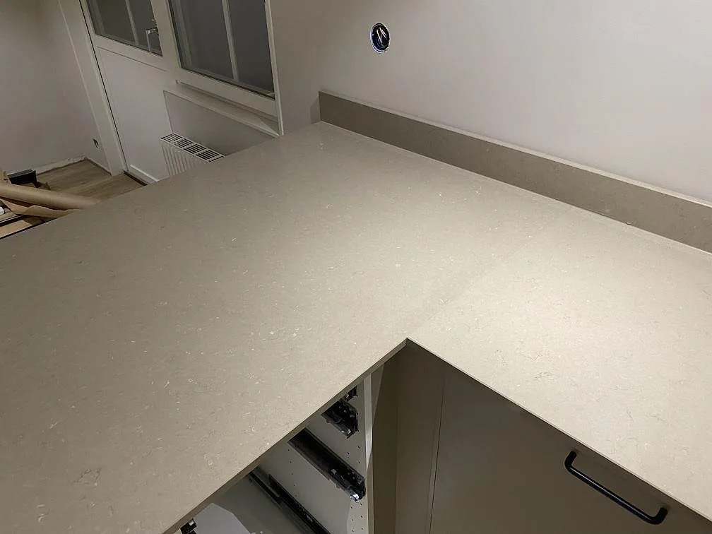 Halvö och hörnsektion i Silestone Coral Clay med låg uppvikt stänkkant i samma greige komposit i ett kök i Karlskrona.
