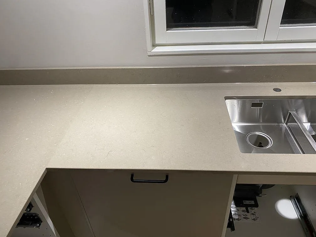 Bänkskiva i Silestone Coral Clay med underlimmad rostfri dubbelho och uppvikt stänkkant under fönstret i ett kök i Karlskrona.