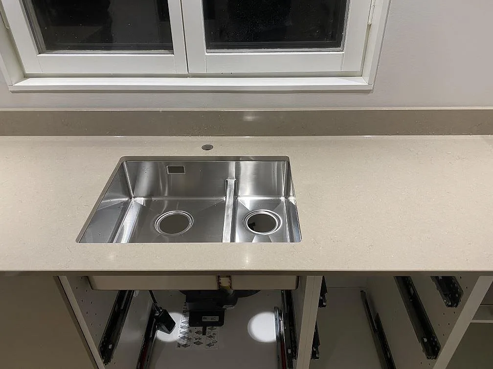 Underlimmad dubbelho i rostfritt stål infälld i polerad Silestone Coral Clay under köksfönstret i Karlskrona.