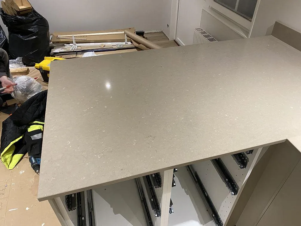 Svängd köksö i polerad Silestone Coral Clay sedd ovanifrån under montering i ett kök i Karlskrona.
