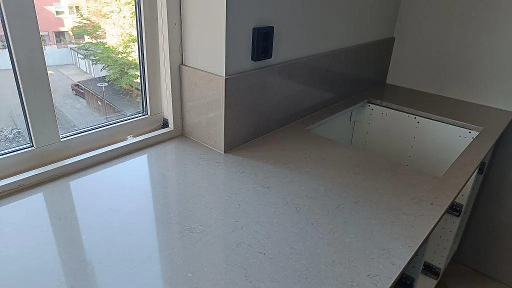 Sidodel av köksbänkskiva i polerad Silestone Coral Clay med 12 mm stänkskydd och rektangulärt hälluttag i Karlskrona.
