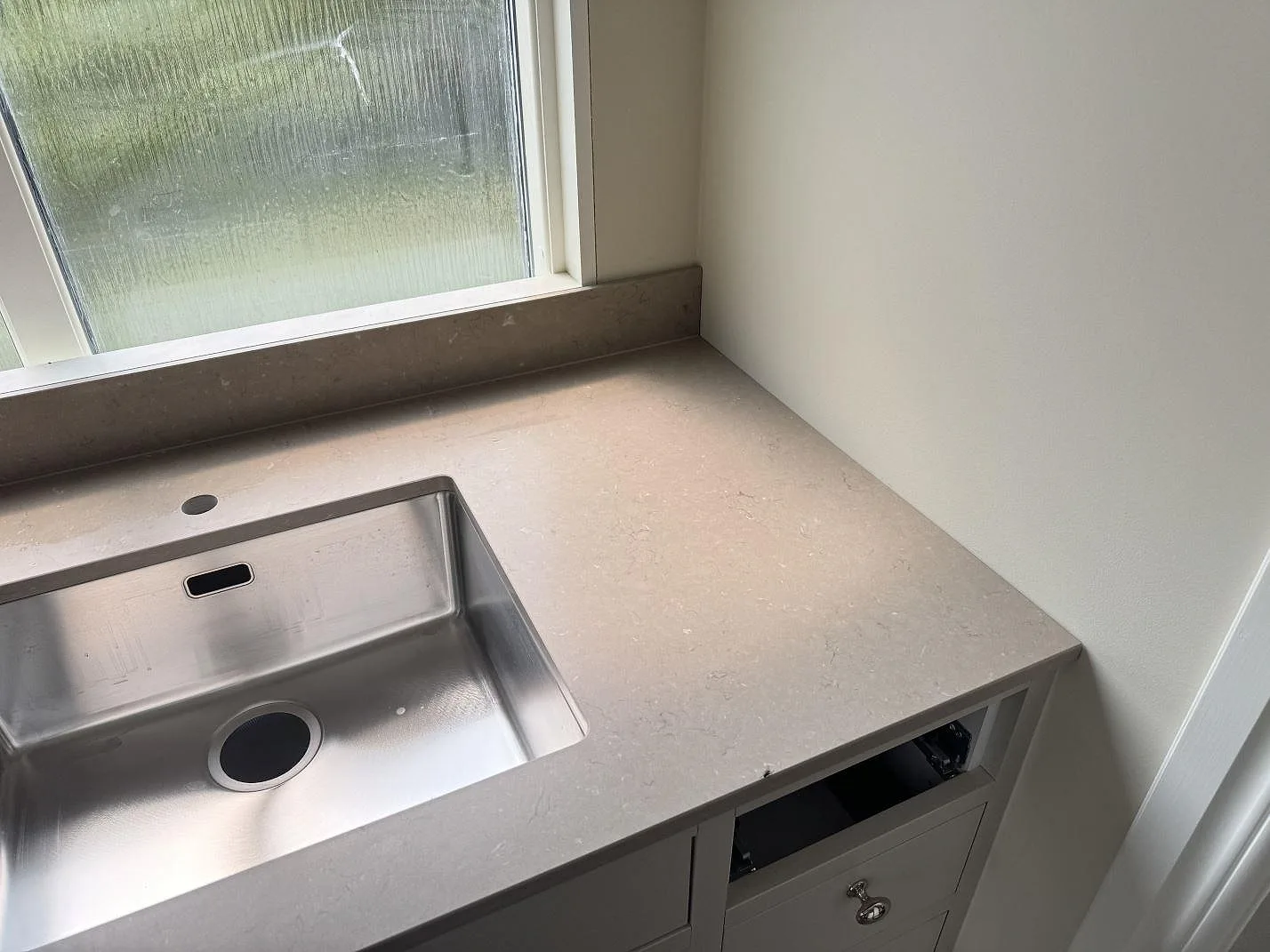 Bänkskiva i Silestone Coral Clay, matt Mocka, vid fönster med rostfri diskho och låg stänkkant i Karlskrona.