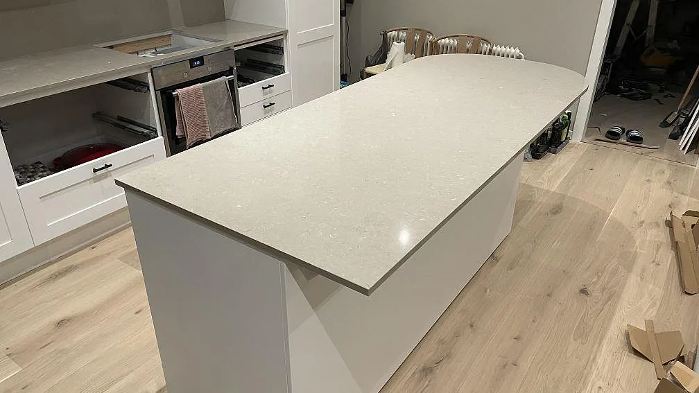 Polerad köksö i Silestone Coral Clay, ljus kvartskomposit med rundad kortsida, under montering i ett kök i Karlskrona.