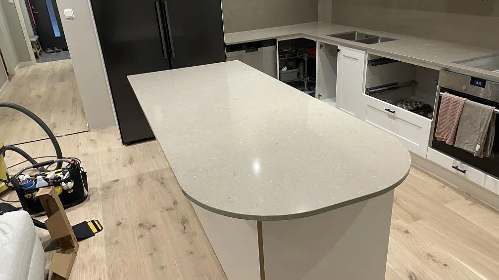 Köksö med rundad kortsida i polerad Silestone Coral Clay och bakre bänkskivor i samma kvartskomposit i Karlskrona.
