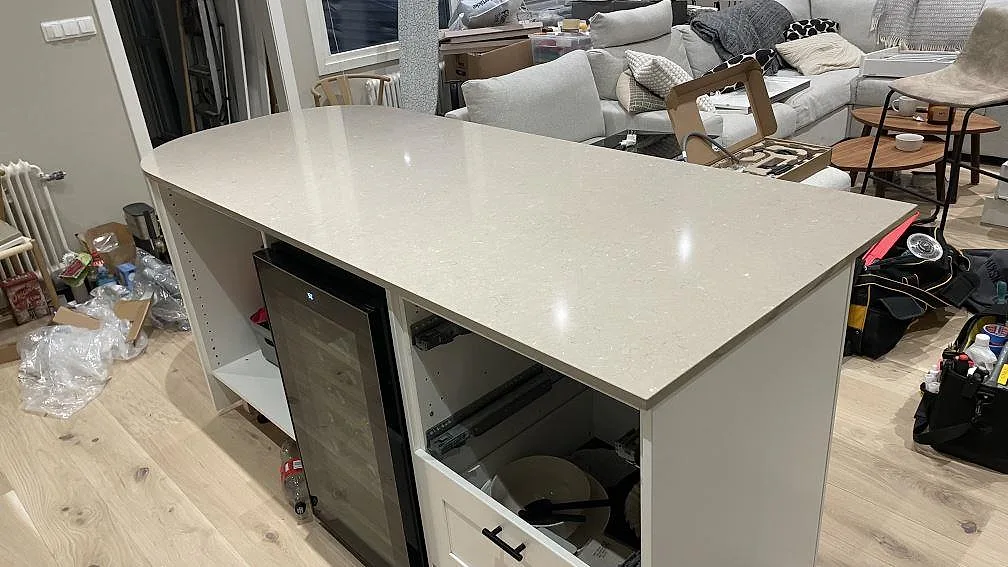 Köksö i polerad Silestone Coral Clay med ljus gråbeige yta och synliga monteringsverktyg i ett kök i Karlskrona.