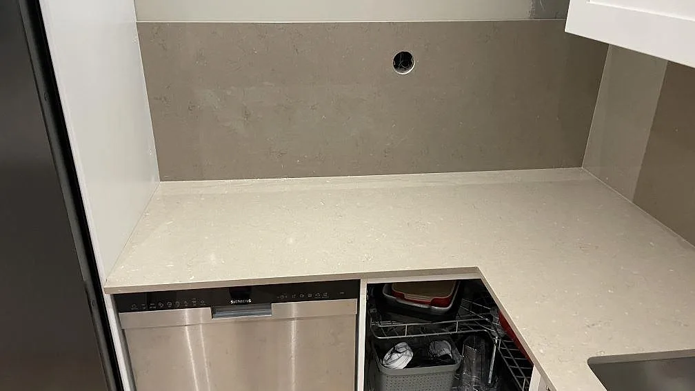 Bakre köksbänkskiva i polerad Silestone Coral Clay med stänkskydd i samma kvartskomposit och öppen stomme i Karlskrona.