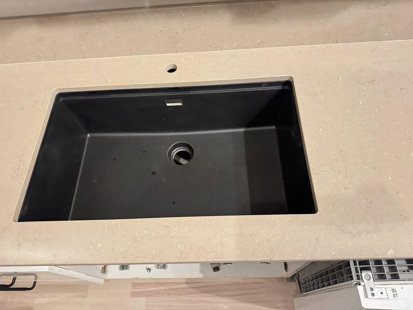 Detalj av svart diskho i köksbänkskiva av polerad Silestone Coral Clay med blandarhål och ljus ådring i Karlskrona.