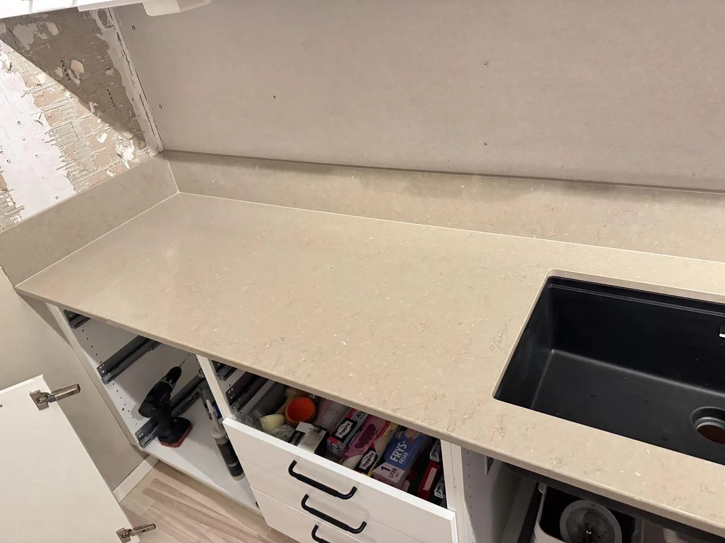 Polerad Silestone Coral Clay som köksbänkskiva och stänkkant vid svart diskho och öppna köksstommar i Karlskrona.