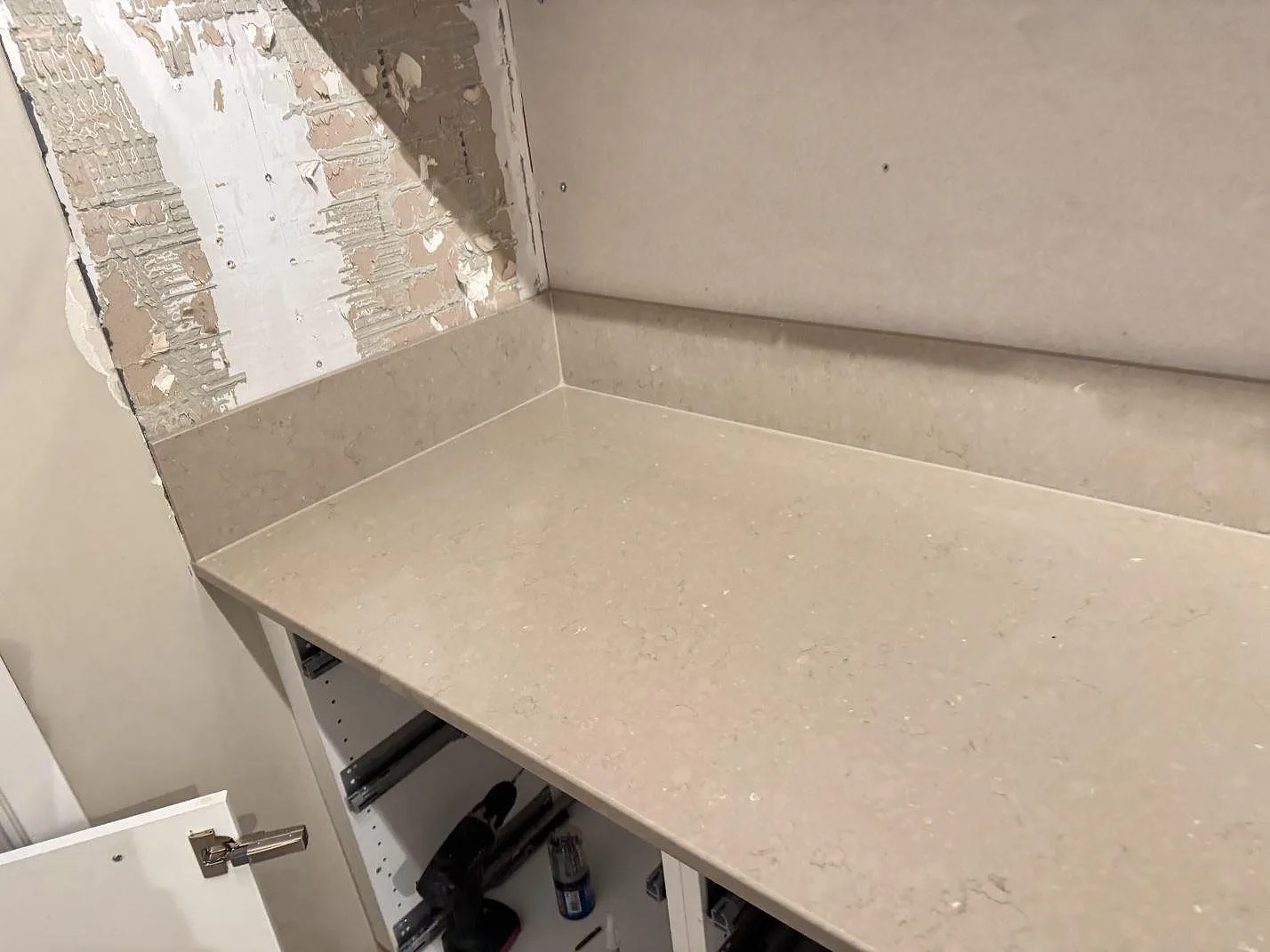 Hörnsektion med köksbänkskiva och låg stänkkant i polerad Silestone Coral Clay under montering i Karlskrona.