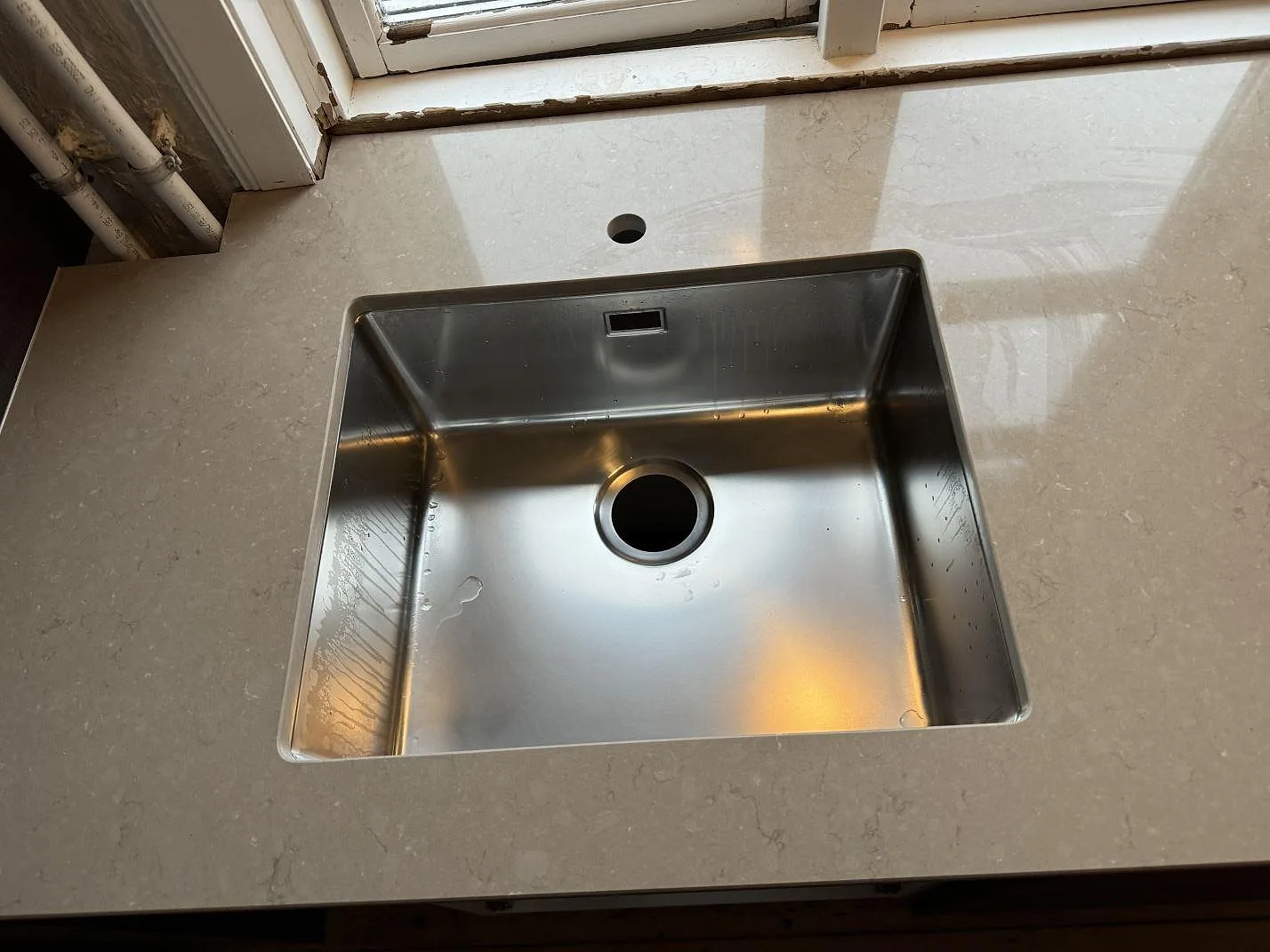 Närbild på underlimmad rostfri diskho i polerad Silestone Coral Clay bänkskiva i Kastrup.