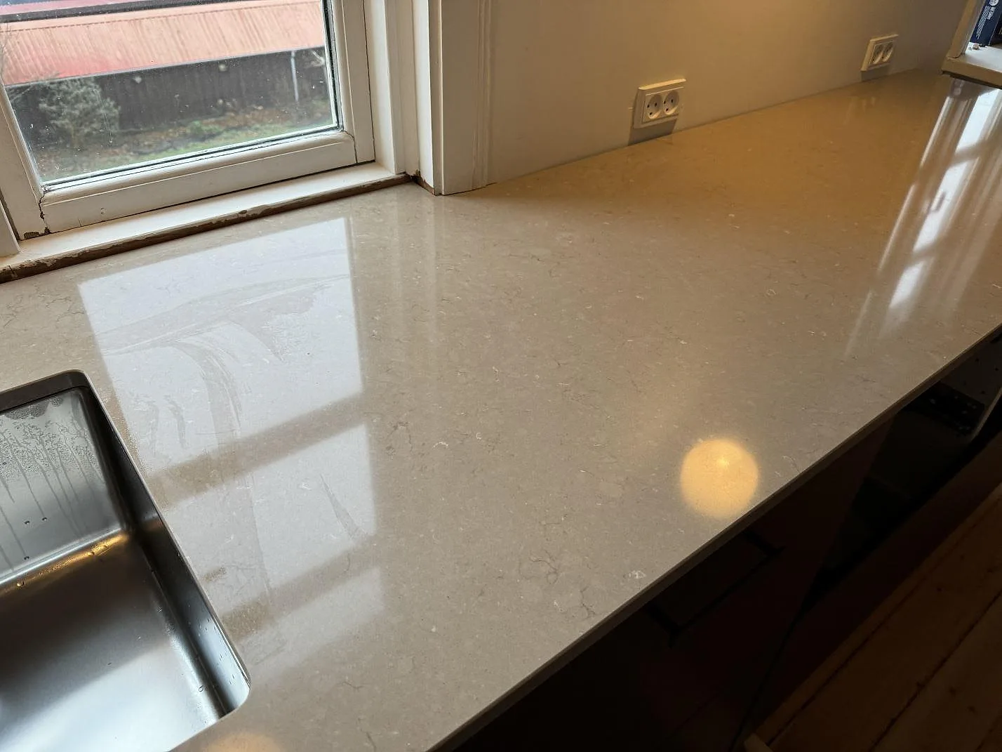 Blank yta i polerad Silestone Coral Clay, 20 mm komposit, på köksbänk med diskho och vägguttag i Kastrup.