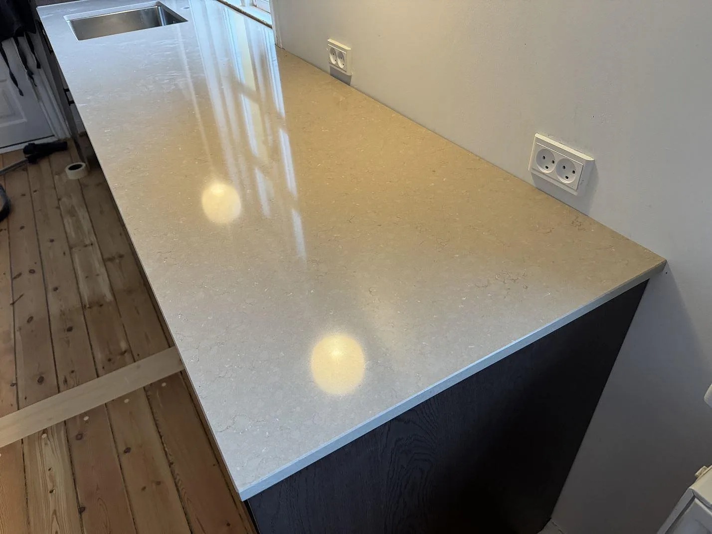 Lång polerad bänkskiva i Silestone Coral Clay komposit med diskhozonen vid fönster i Kastrup.