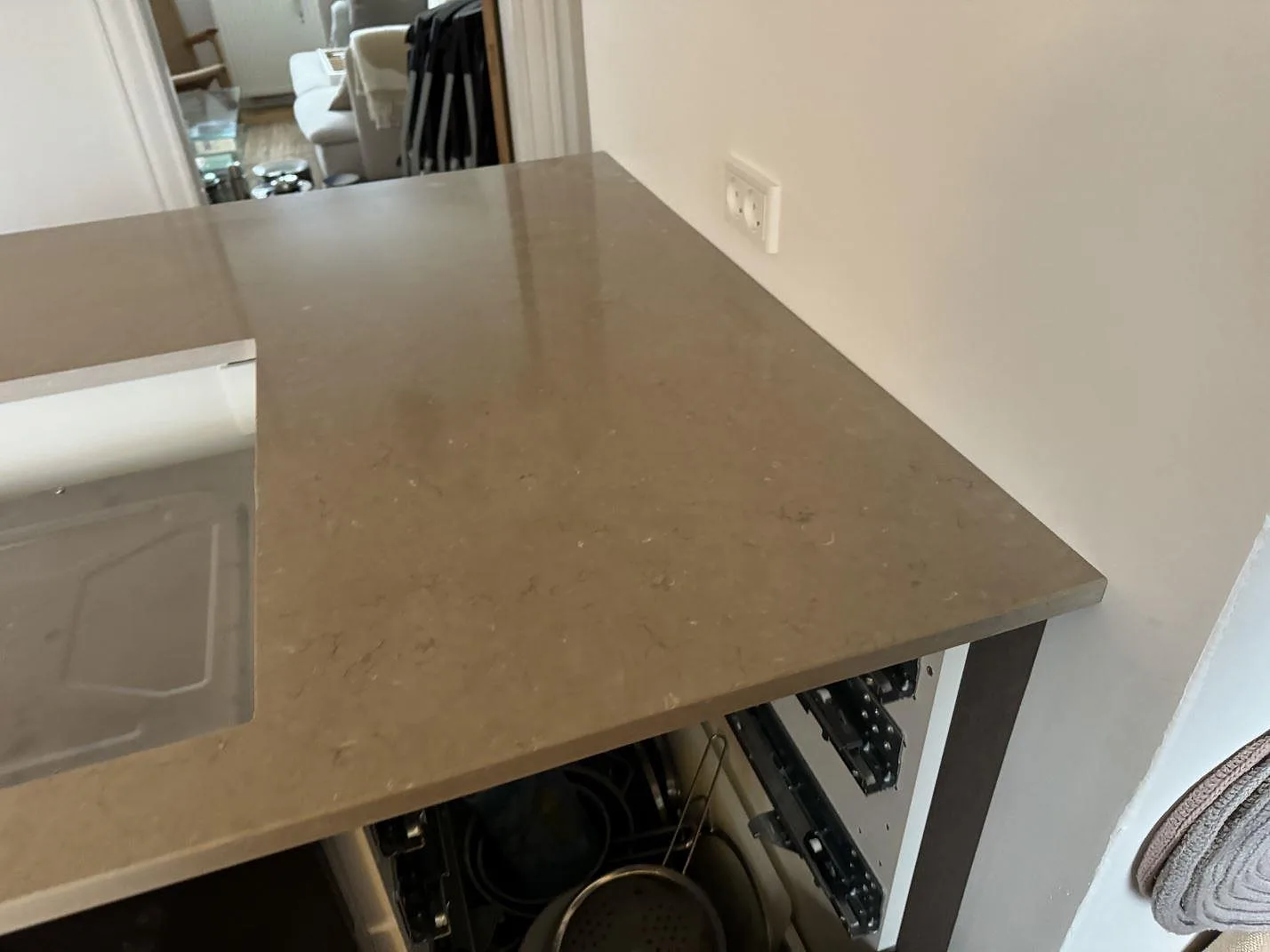 Sidovy över polerad Silestone Coral Clay bänkskiva på köksö med öppen stomme under montering i Kastrup.