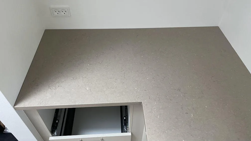 Rak väggbänk i polerad Silestone Coral Clay med varm gråbeige yta och eluttag ovanför i köket i København.