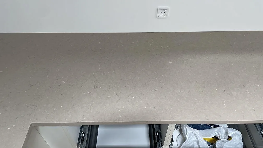 Närbild av polerad Silestone Coral Clay på väggbänk, med fin ljus ådring och öppna köksstommar under montering i København.