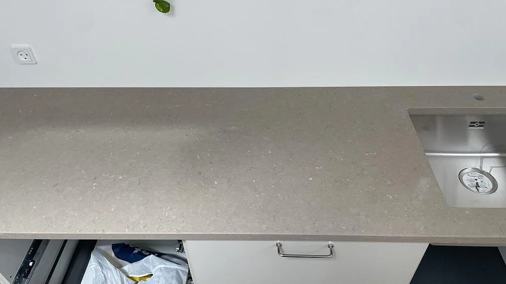 Väggbänk i polerad Silestone Coral Clay med rostfri diskho vid höger kant och öppna underskåp under montering i København.