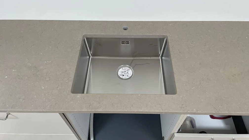 Rostfri diskho i väggbänk av polerad Silestone Coral Clay, gråbeige kvartskomposit, i ett kök i København.