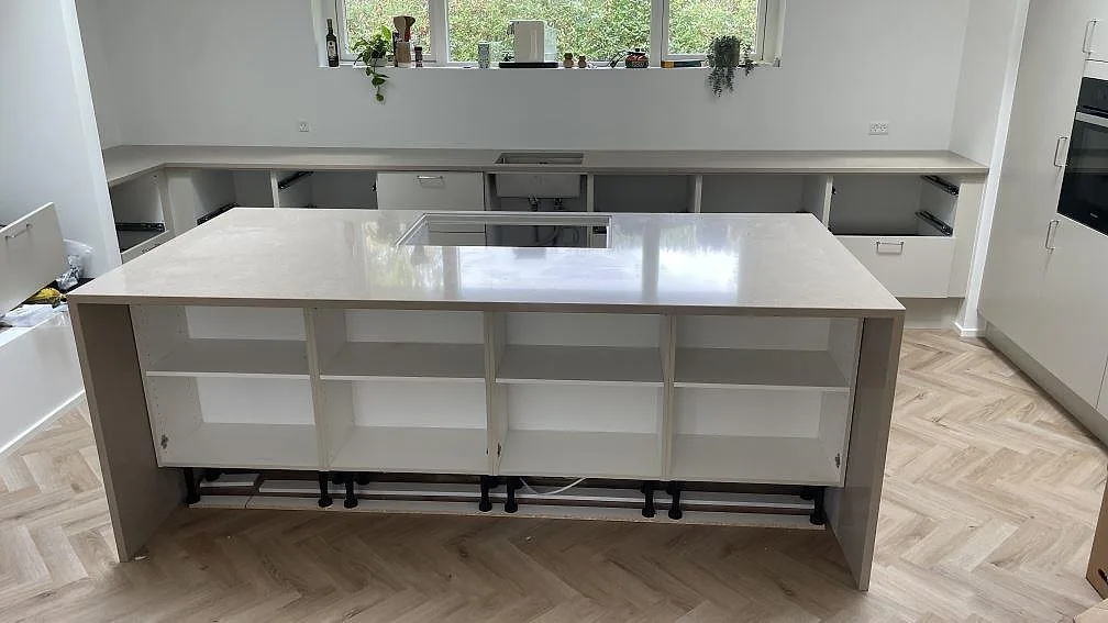 Köksbänkskiva i polerad Silestone Coral Clay, 30 mm kvartskomposit, med stor köksö, väggbänk och synlig hällöppning i ett kök i København.