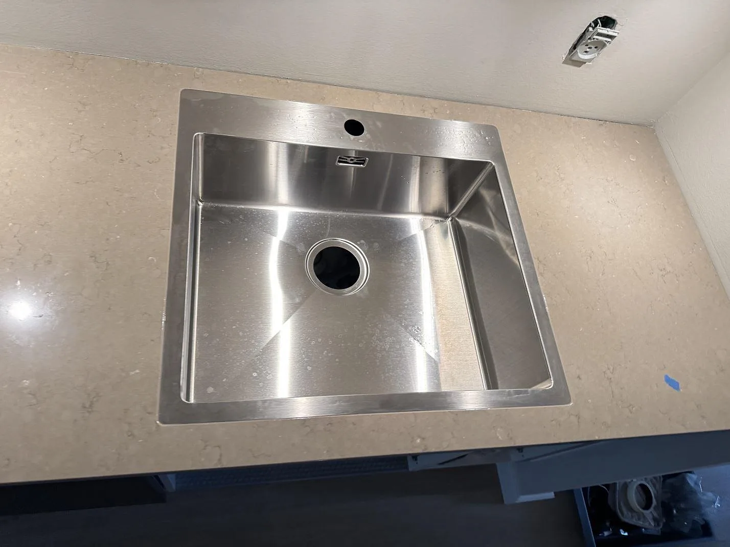 Detalj av rostfri diskho ovanpå polerad Silestone Coral Clay i köket i København.
