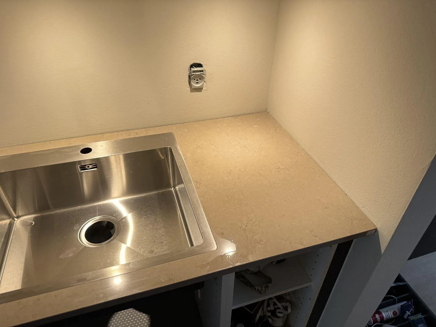 Polerad Silestone Coral Clay runt rostfri diskho och vägganslutning i ett kök i København.