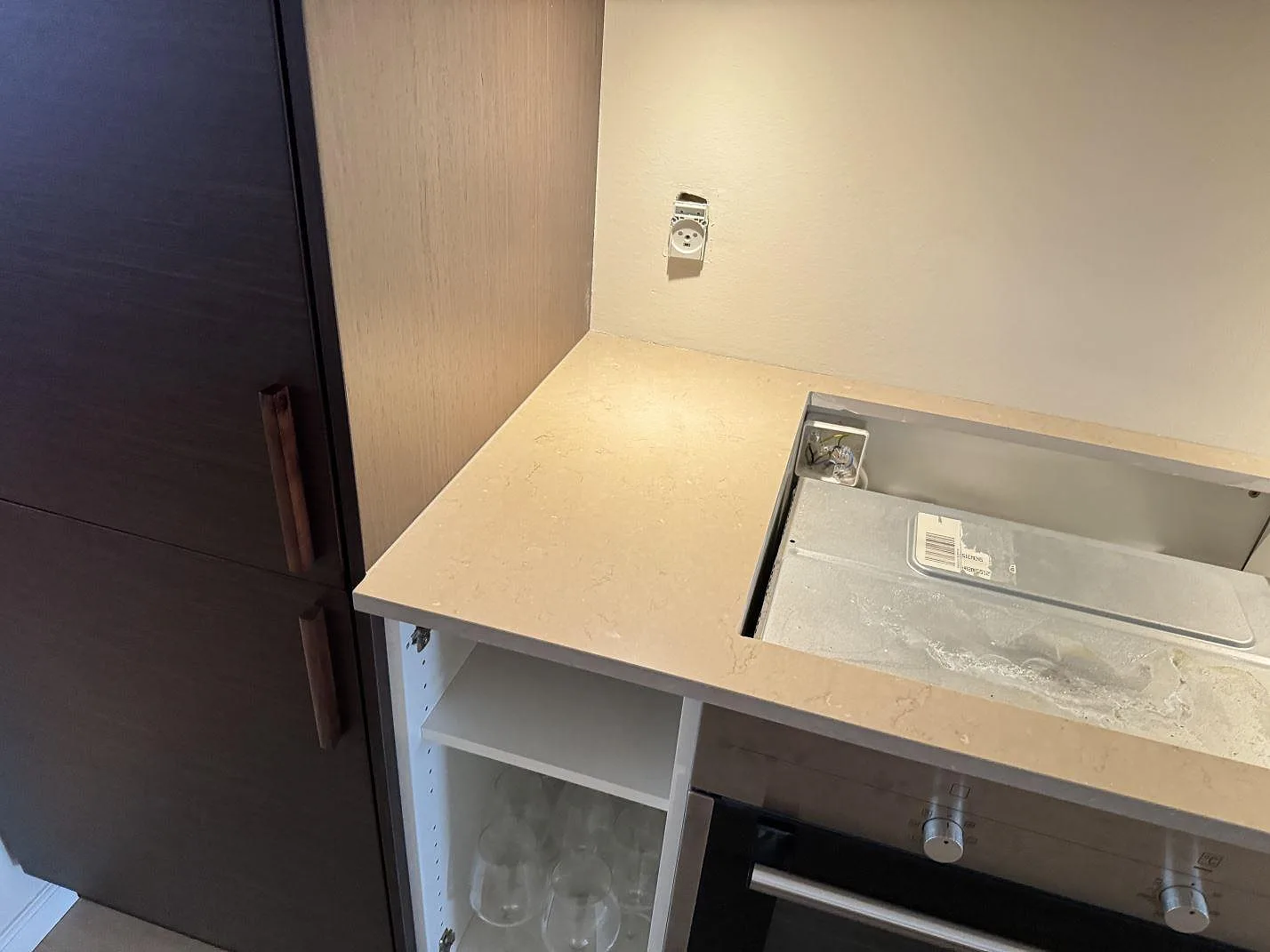 Hörn av köksbänkskiva i polerad Silestone Coral Clay med hällöppning och mörka luckor i København.