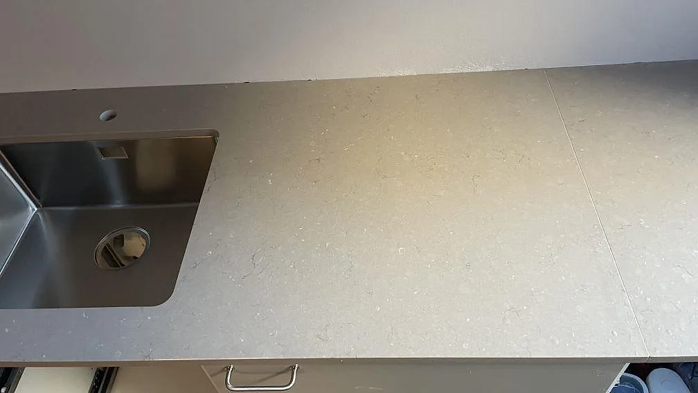 Detalj av lång köksbänkskiva i polerad Silestone Coral Clay med rostfri diskho och skarv i stenen, København N.