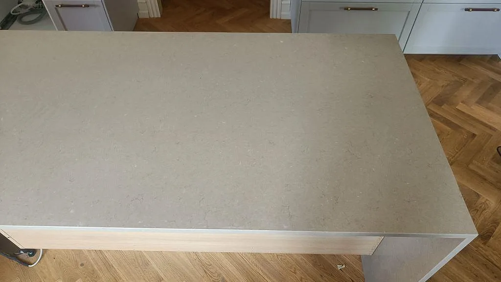 Ovanifrån på den greige stenytan av Silestone Coral Clay på köksön i ett kök i København Ø.