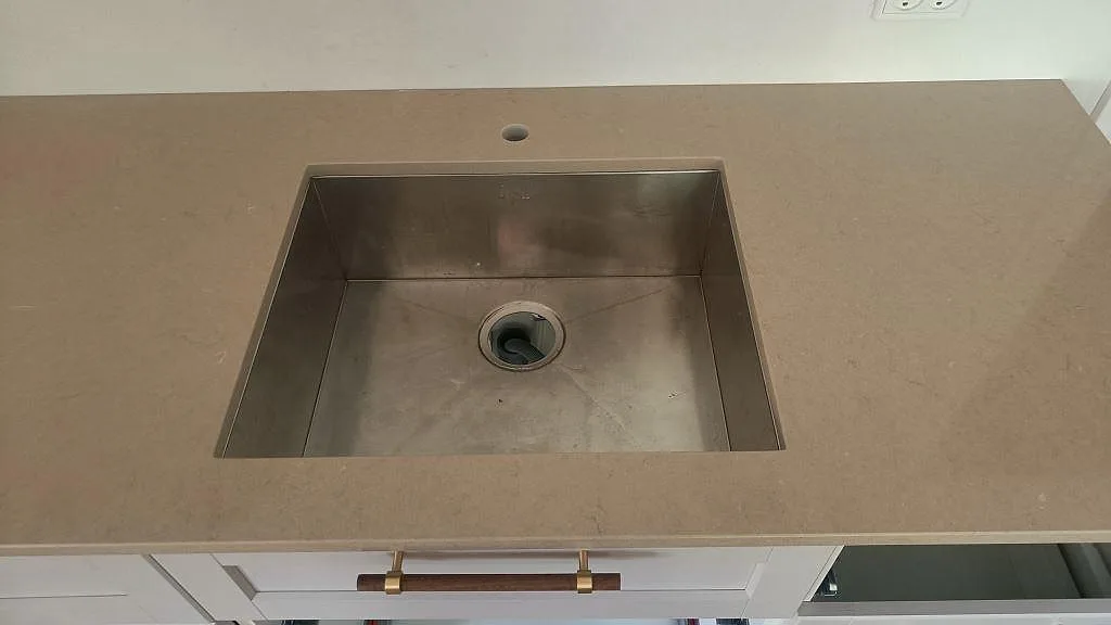Närbild på underlimmad rostfri diskho i en bänkskiva av Silestone Coral Clay i København Ø.