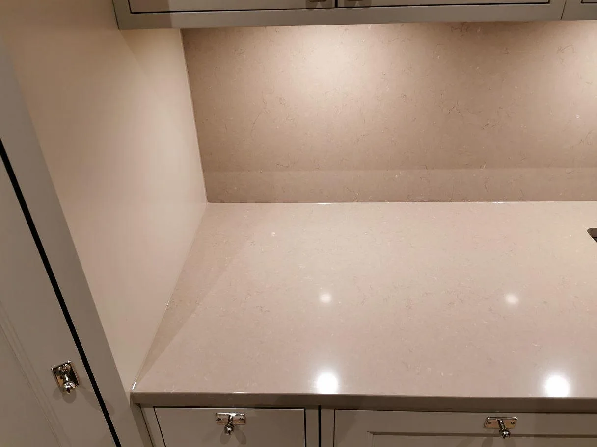 Polerad bänkskiva i Silestone Coral Clay mot uppvikt stänkkant i samma sten längs köksväggen i Kristianstad.
