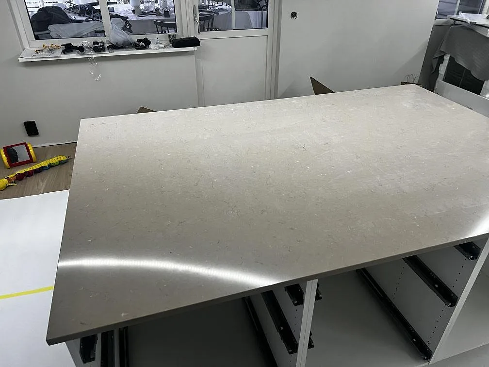Polerad köksö i Silestone Coral Clay med synlig ådring och vita köksstommar i ett Kristianstadskök.