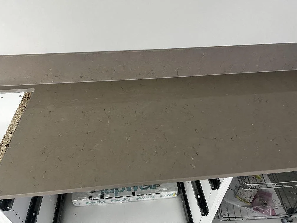 Detalj av väggbänk och stänkskydd i polerad Silestone Coral Clay, greige kvartskomposit, i kök i Kristianstad.