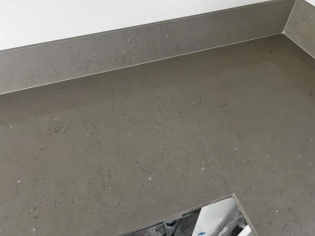 Hörn och skarv i polerad Silestone Coral Clay med låg stänkkant längs väggen i ett kök i Kristianstad.