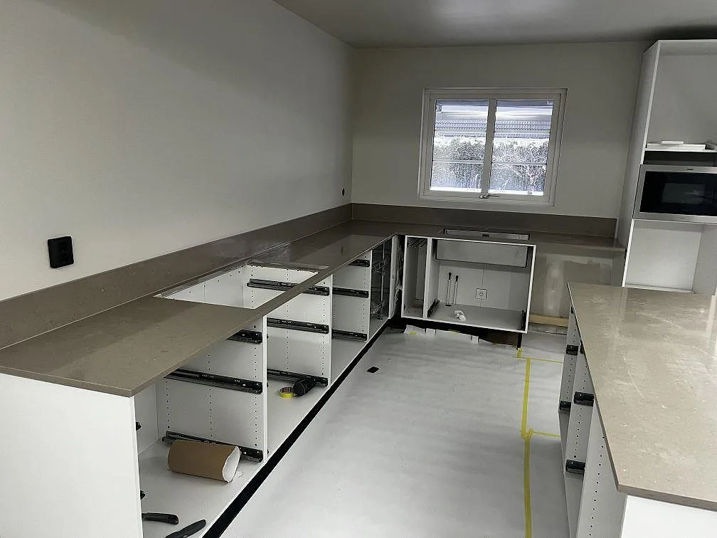 L-format kök med väggbänkar, uppvikt stänkskydd och köksö i polerad Silestone Coral Clay i Kristianstad.