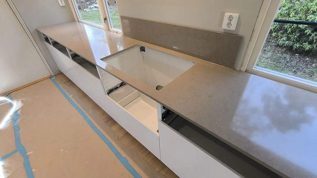 Köksbänkskiva i polerad Silestone Coral Clay med öppning för häll och uppvikt stänkskydd i Kungsängen.