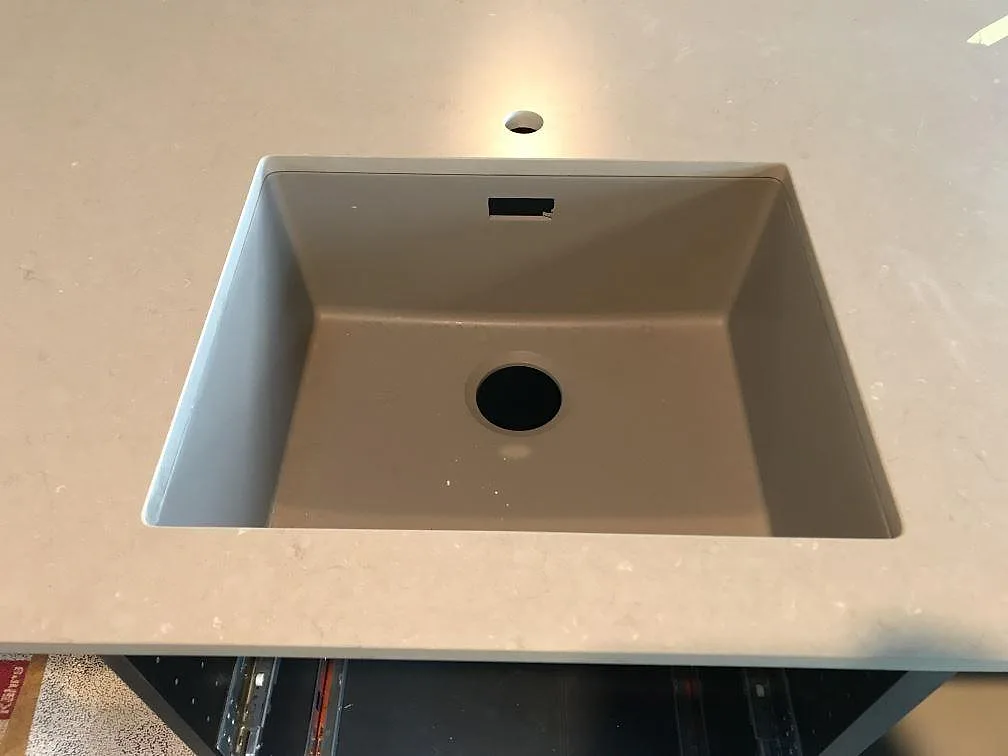 Köksbänkskiva i matt Silestone Coral Clay med rektangulär diskho och kranhål i en gråbeige komposityta i Kungsbacka.