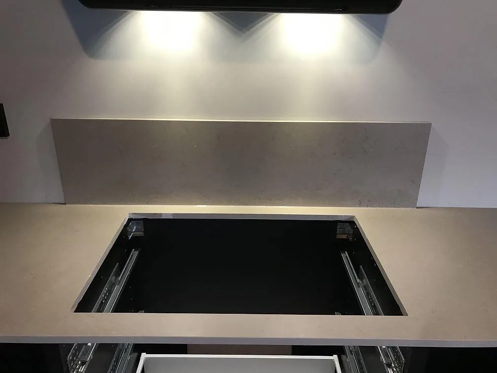 Bänkskiva i matt Silestone Coral Clay med fristående stänkskydd och urtag för häll i ett kök i Kungsbacka.