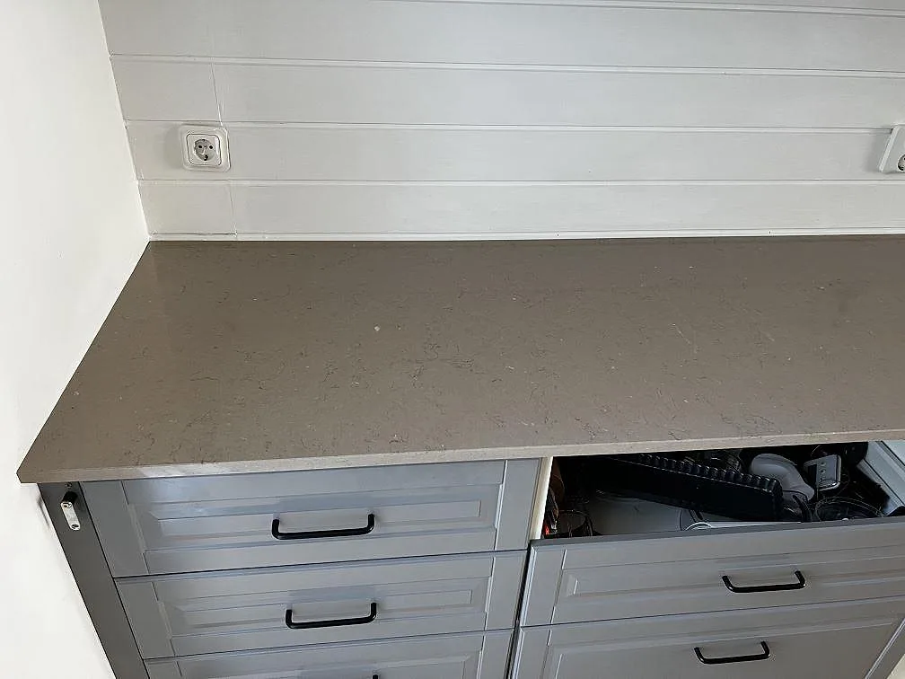 Köksbänkskiva i Silestone Coral Clay, polerad i en varm lergrå ton, monterad på grå lådfronter med svarta handtag i ett kök i Kungsbacka.